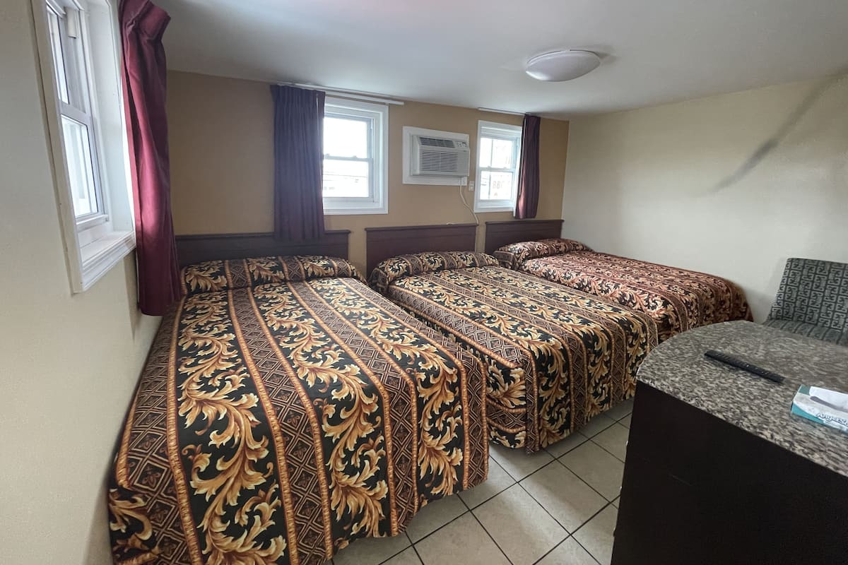 A room with two beds, a desk, and a window.