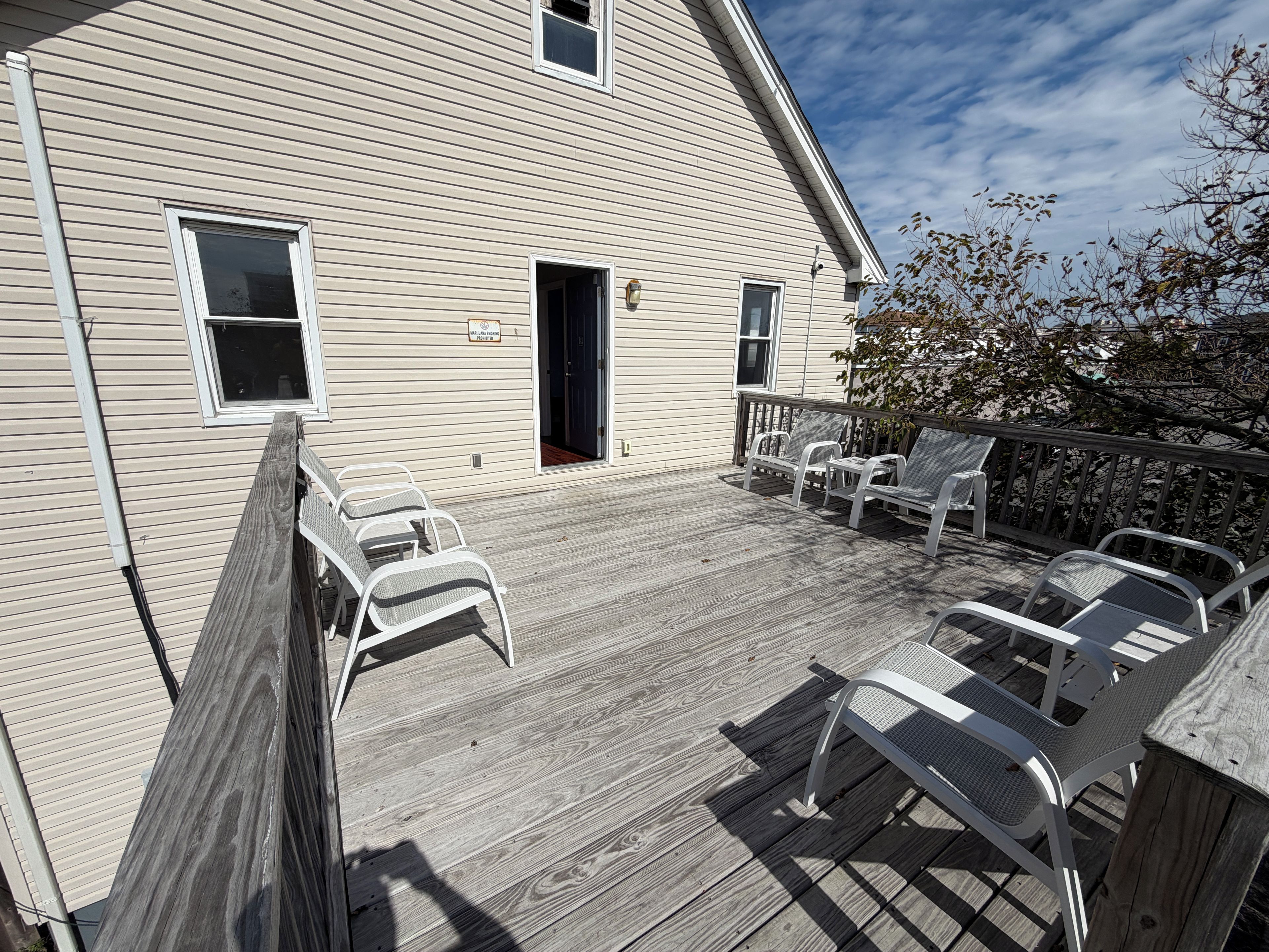 A wooden deck with outdoor furniture, a building with windows, and a door.