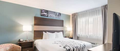 A hotel room with a bed, nightstands, a chair, a TV, and a window with curtains.