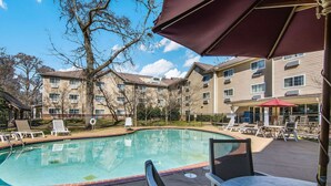 A swimming pool with lounge chairs and umbrellas, surrounded by apartment buildings. - Sleep Inn & Suites Columbus near Fort Benning (Columbus)