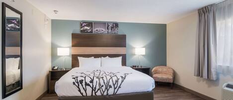 A hotel room with a large bed, two bedside tables, a chair, and artwork on the wall.
