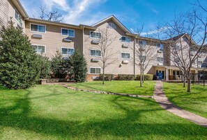A multi-story residential building with a well-maintained lawn, trees, and a pathway leading to the entrance. - Sleep Inn & Suites Columbus near Fort Benning (Columbus)