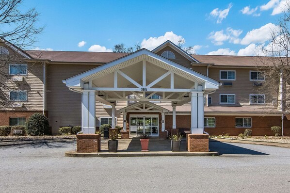 A hotel entrance with a covered walkway, brick pillars, and potted plants. - Sleep Inn & Suites Columbus near Fort Benning (Columbus)