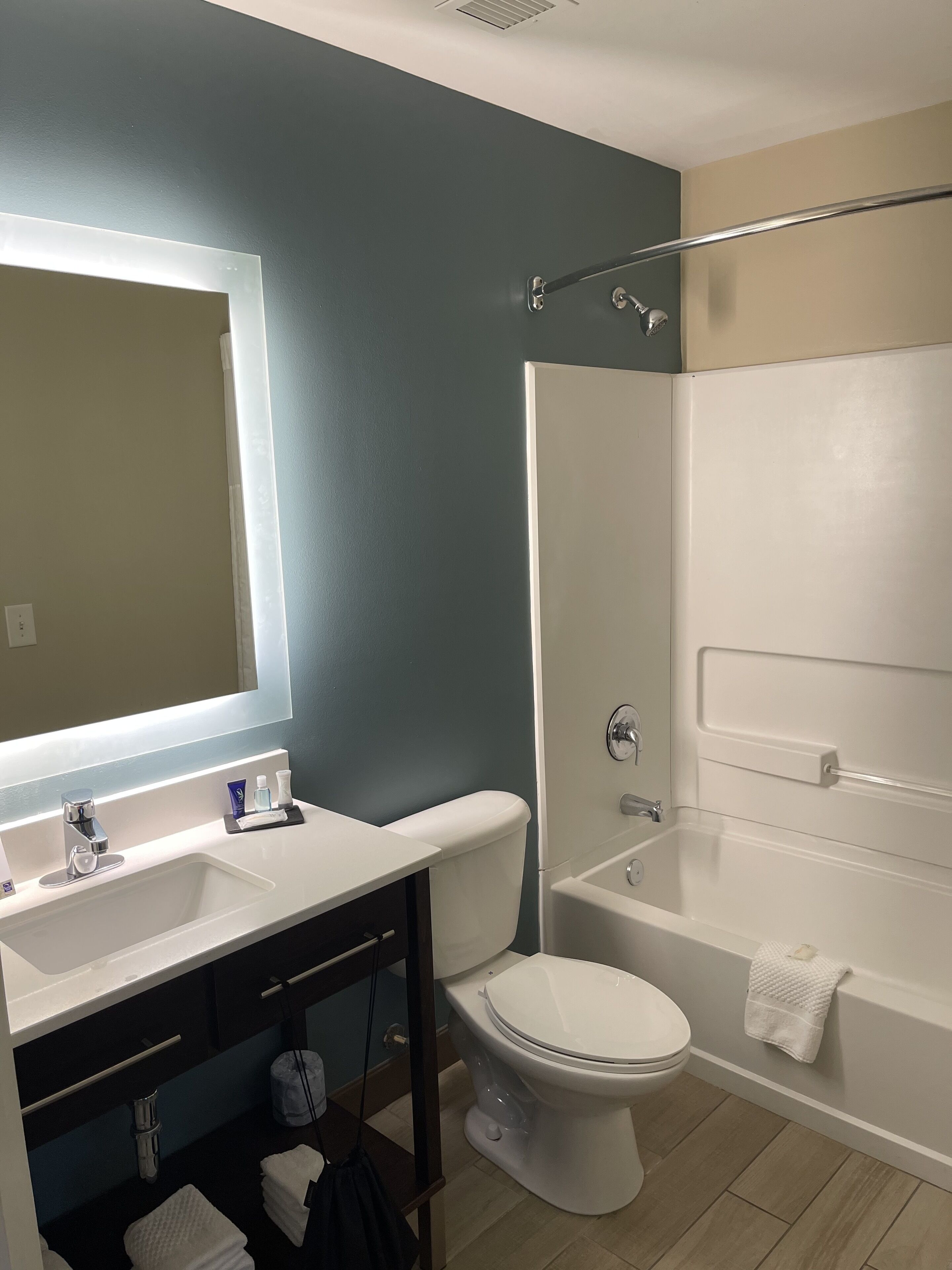 A bathroom with a white sink, mirror, and toilet, a bathtub, and a shower area.
