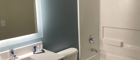 A bathroom with a white sink, mirror, and toilet, a bathtub, and a shower area.