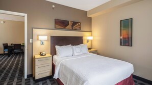 Hotellihuone, jossa on suuri sänky, kaksi yöpöytää, työpöytä ja tuoleja.