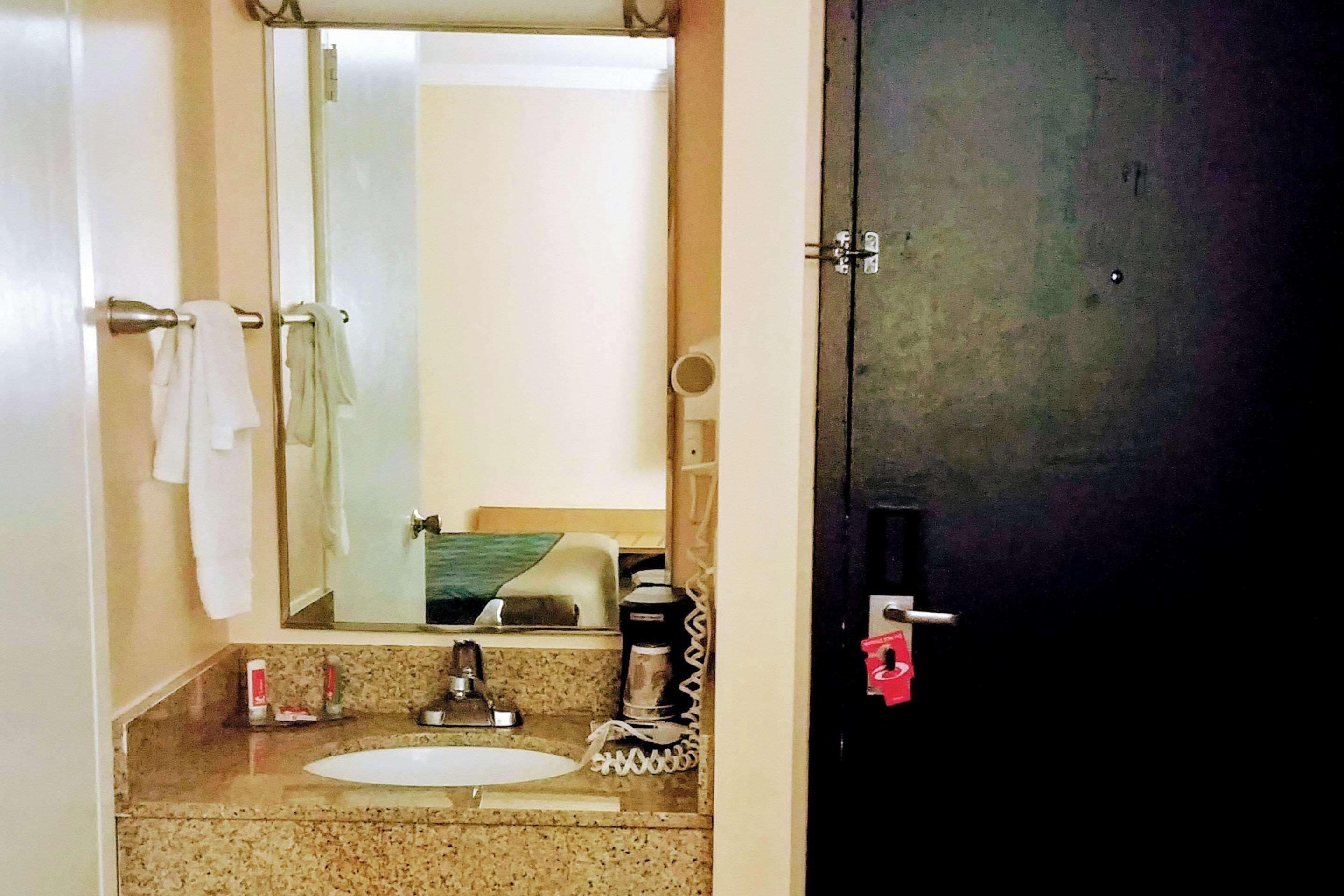 A bathroom with a sink, mirror, and towel rack.