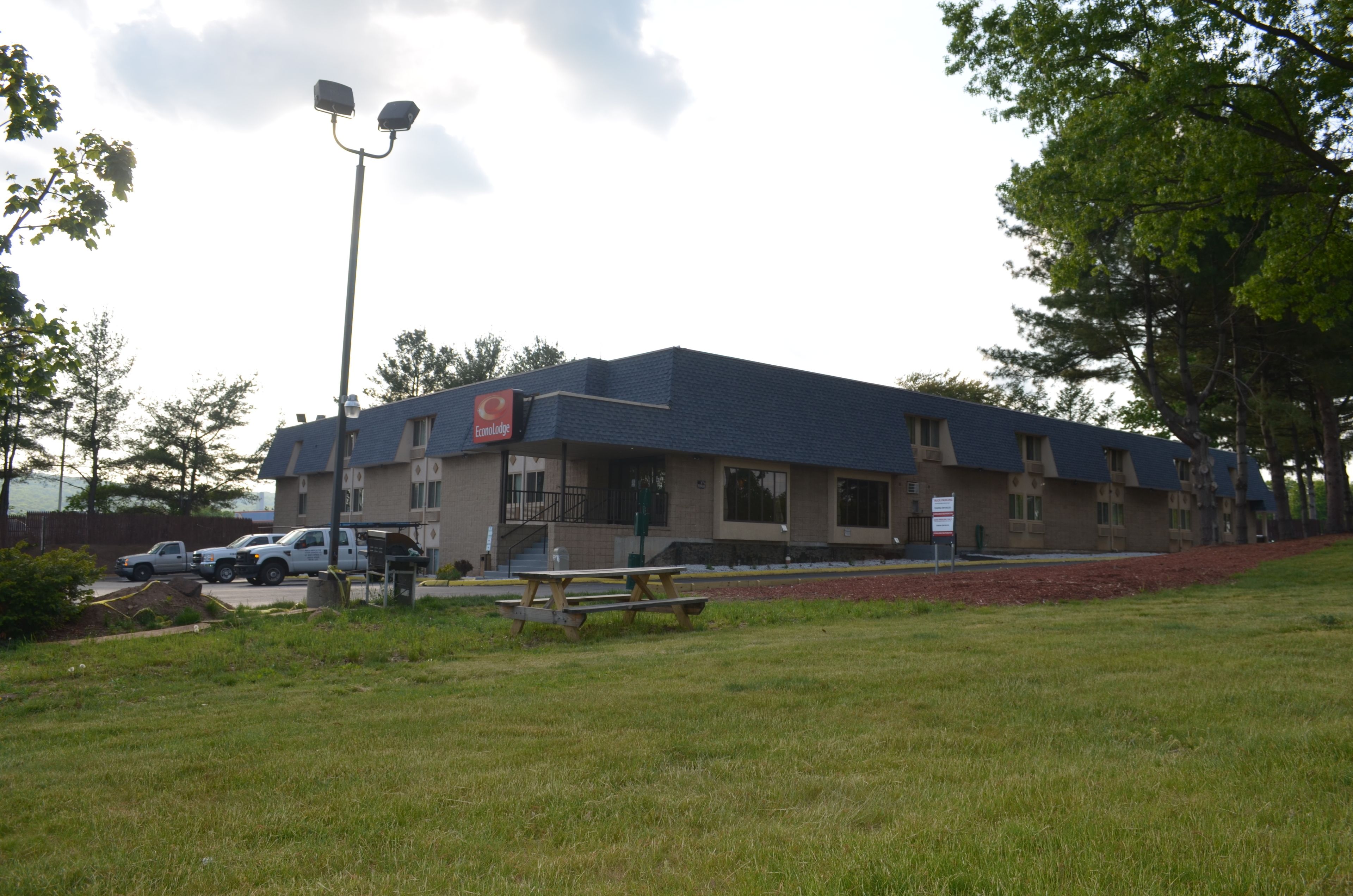 A building with a flat roof, a parking lot, and a picnic table.