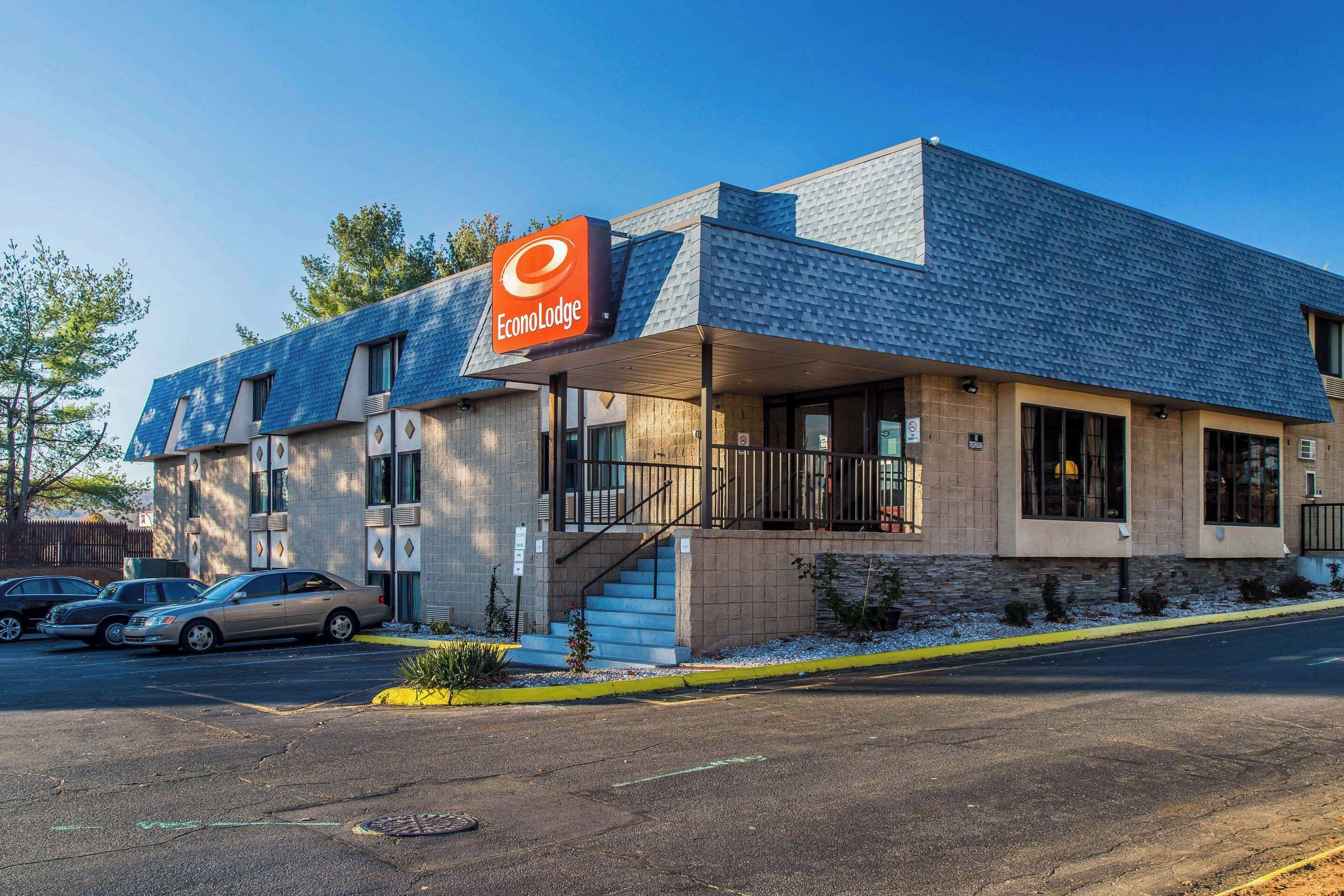 A modern hotel with a prominent sign, a covered entrance, and a parking lot.