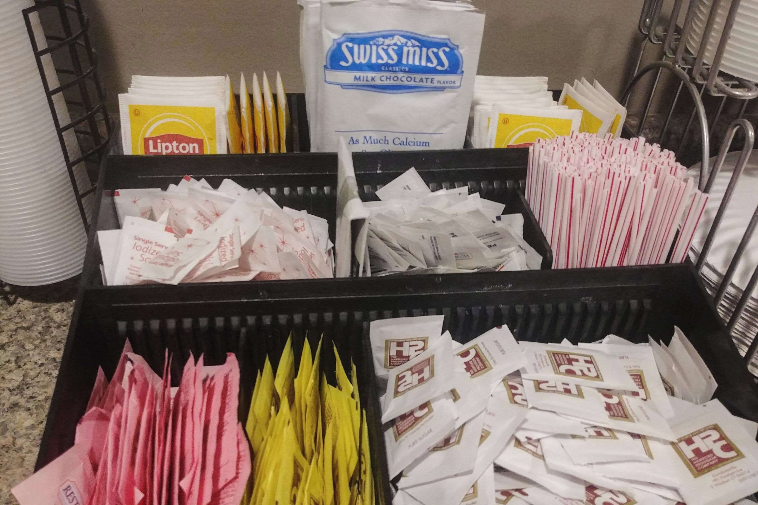 A storage area with various bags of food products, including Lipton tea, Swiss Miss milk chocolate, and other items.