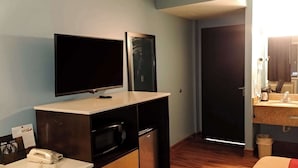 Ein Hotelzimmer mit Flachbildfernseher, Mikrowelle, kleinem Kühlschrank, Telefon und Waschbecken mit Spiegel.