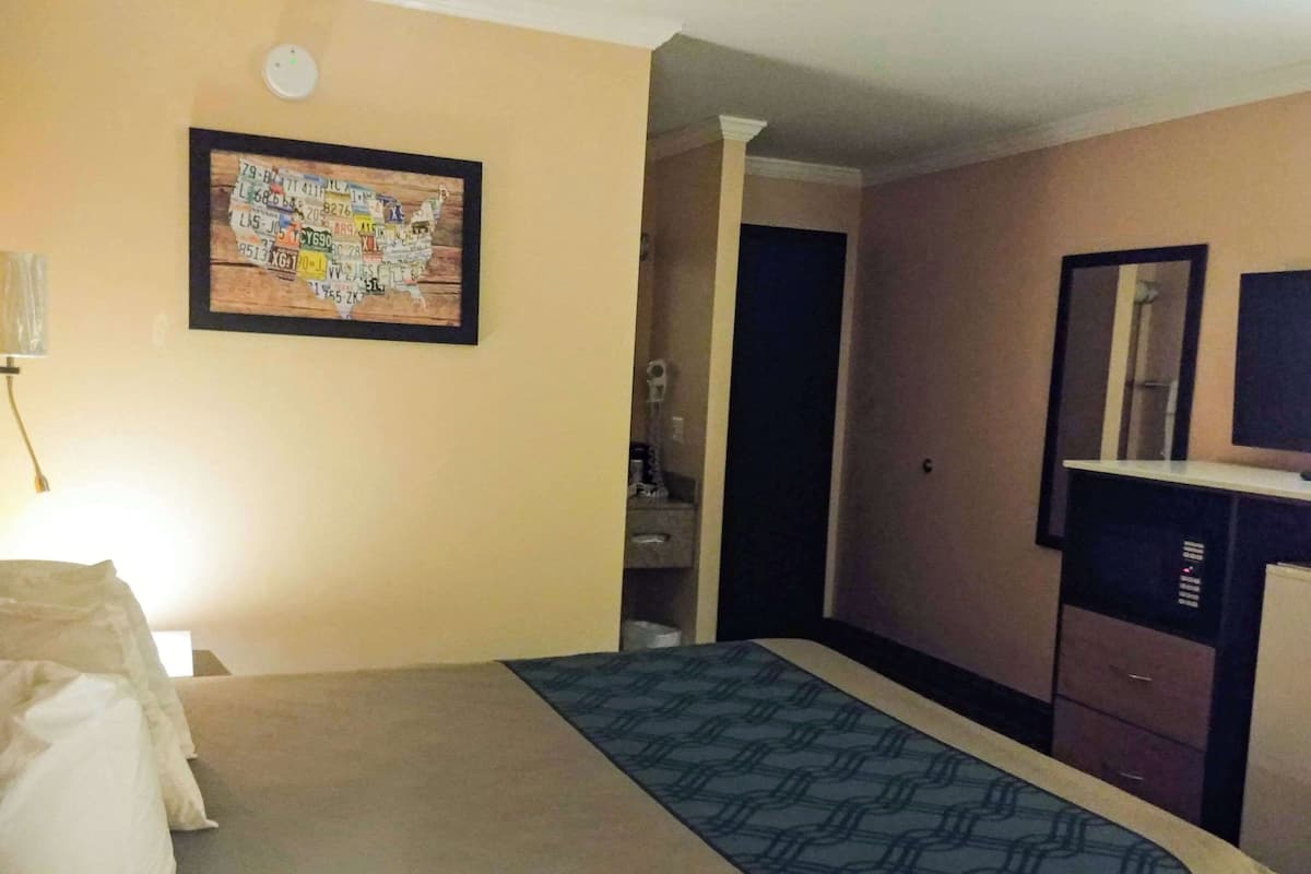 Une chambre d’hôtel équipée d’un lit, d’un bureau, d’un miroir et d’une carte accrochée au mur.