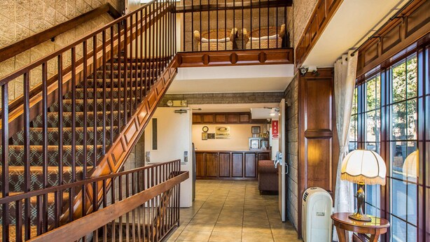 Eine Hotlellobby mit einer Holztreppe, einem Empfangsbereich und Blick durch große Fenster.