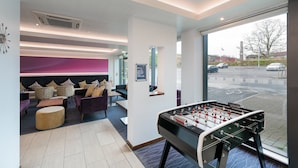 Eine moderne Lobby mit einem Kicker, gemütlicher Sitzgelegenheiten und Blick auf die Straße.