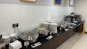Ein Buffet mit verschiedenen Servierstationen, darunter warme und kalte Speisen sowie eine Kaffeestation.