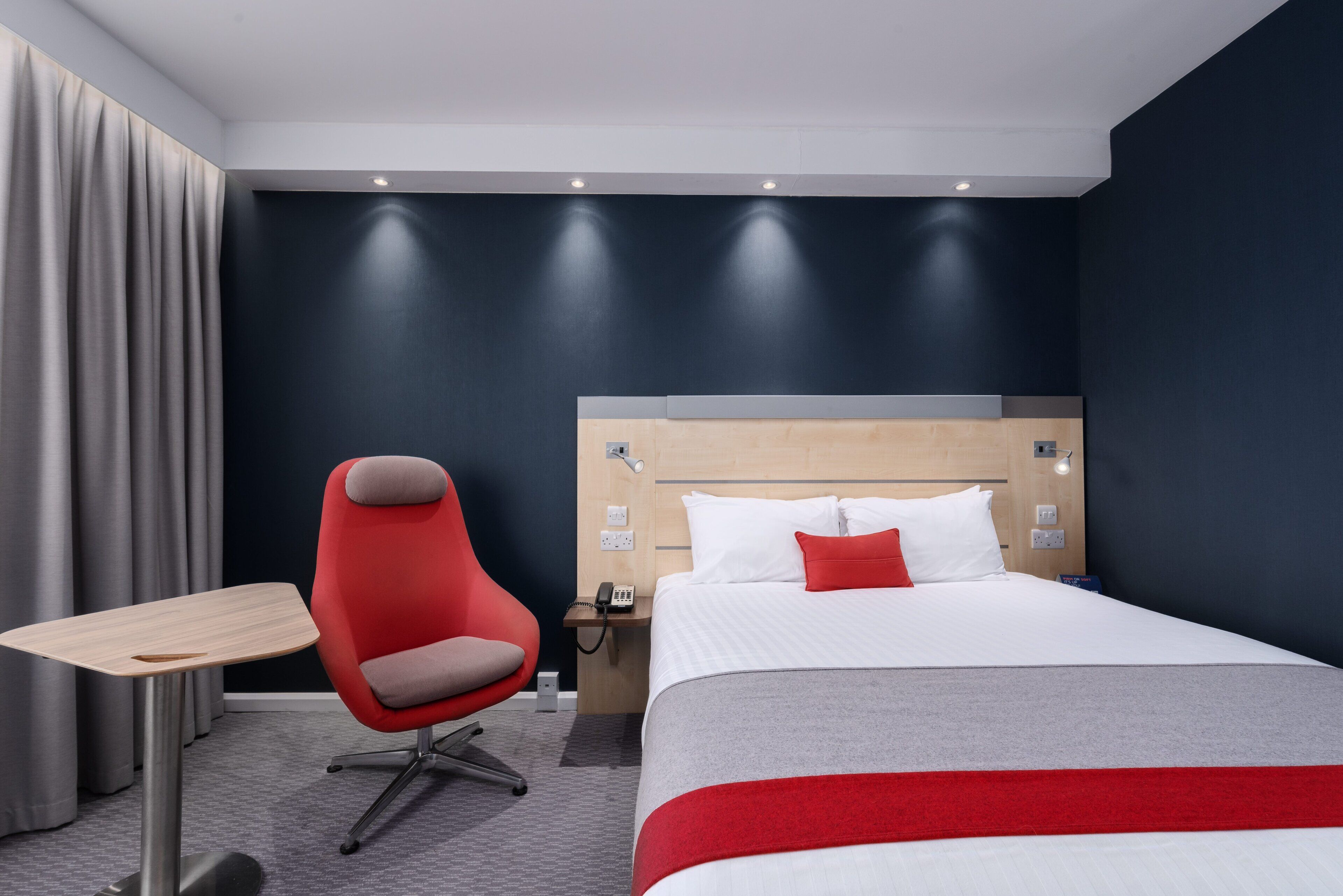 Una habitación de hotel con cama, escritorio, silla y mesita de noche.