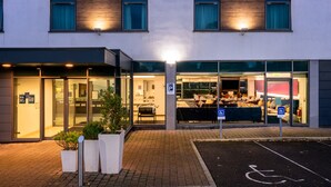 Ein Hotel mit Glasfassade, Parkplatz und Rollstuhlgerechter Kennzeichnung.