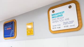 Eine Wand mit drei Schildern: eines zur Frühstückszeit, eines mit Werbung für Speck und eines bezüglich Allergien.