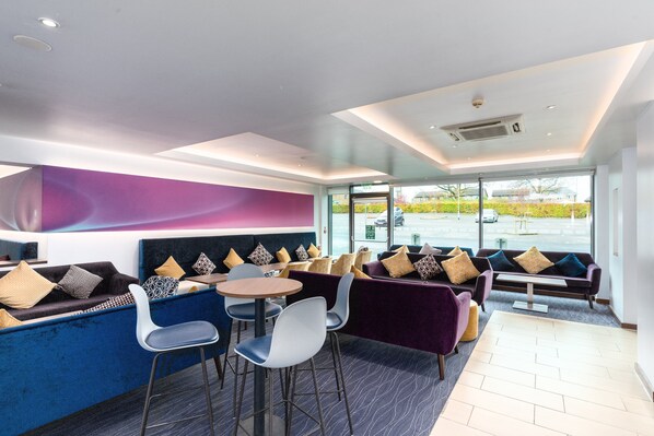 A modern interior with seating areas, tables, and a view through large windows. - Holiday Inn Express Hotel Burnley M65 JCT10 by IHG (Burnley)