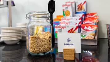 Una mesa de desayuno con un tarro de granola, una cuchara y varias cajas de cereales.