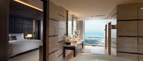 Una habitación de hotel moderna con una cama grande, un baño con bañera y vistas a la ciudad.