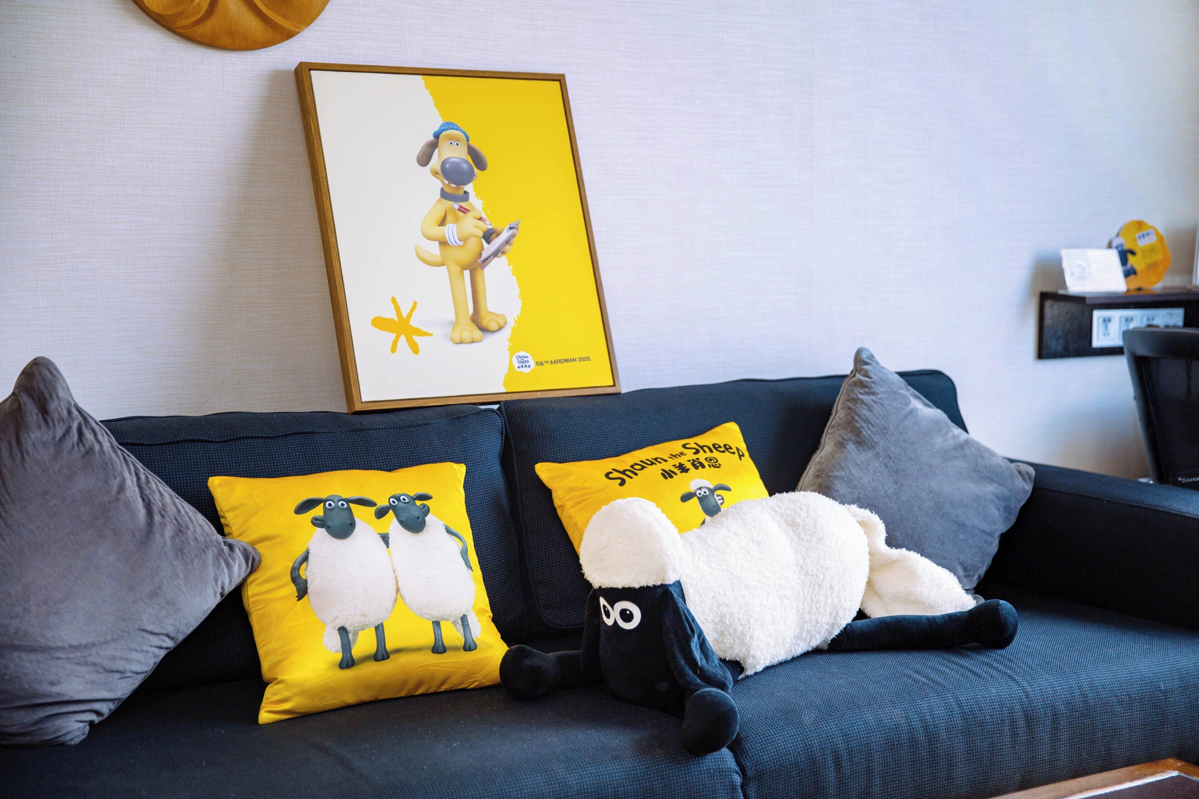 A dark blue sofa with three pillows, one featuring a sheep design and another with a dog illustration.