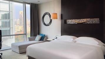 Une chambre d’hôtel moderne avec un grand lit, un canapé, un bureau et une vue sur la ville.