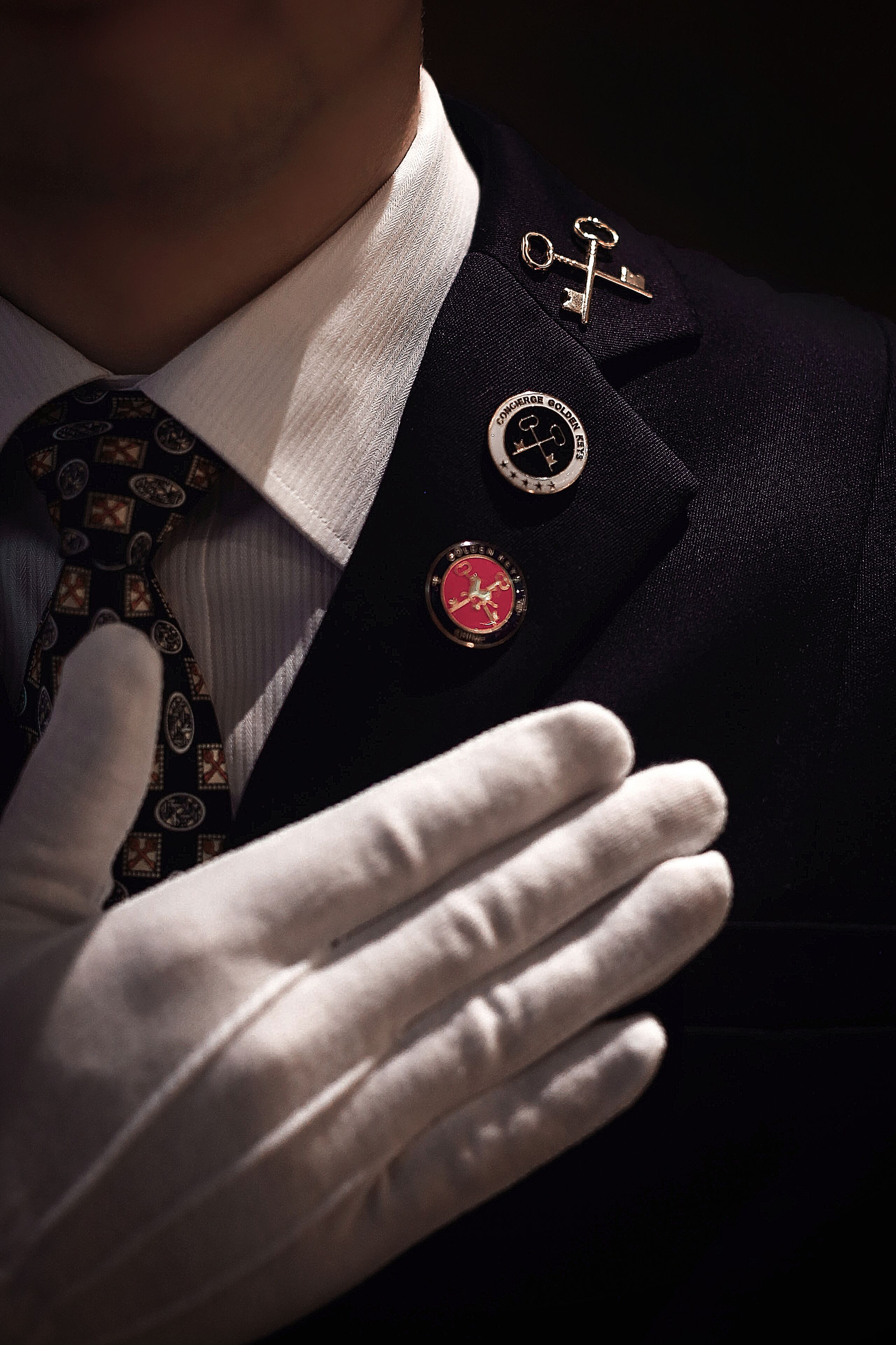 A person wearing a dark suit with a white shirt and a patterned tie.