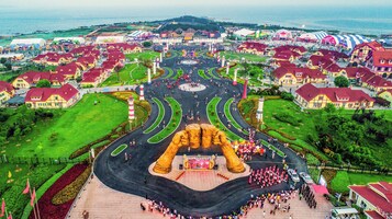 Una amplia plaza abierta con un escenario central, rodeada por una carretera circular con varios puntos de acceso y salida.