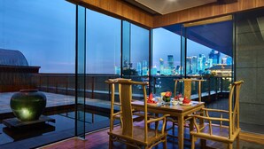 A dining area with a view of a city skyline at dusk. - InterContinental Qingdao by IHG (Qingdao)