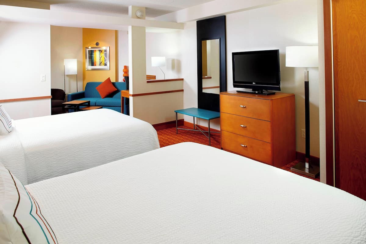 Une chambre d’hôtel avec deux lits, une télévision, une commode, un bureau et une chaise.