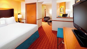 Una habitación de hotel con una cama grande, televisión, escritorio y silla.