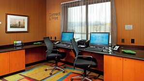 Un salón de conferencias con dos escritorios, sillas, un cuadro enmarco y una ventana con vistas.