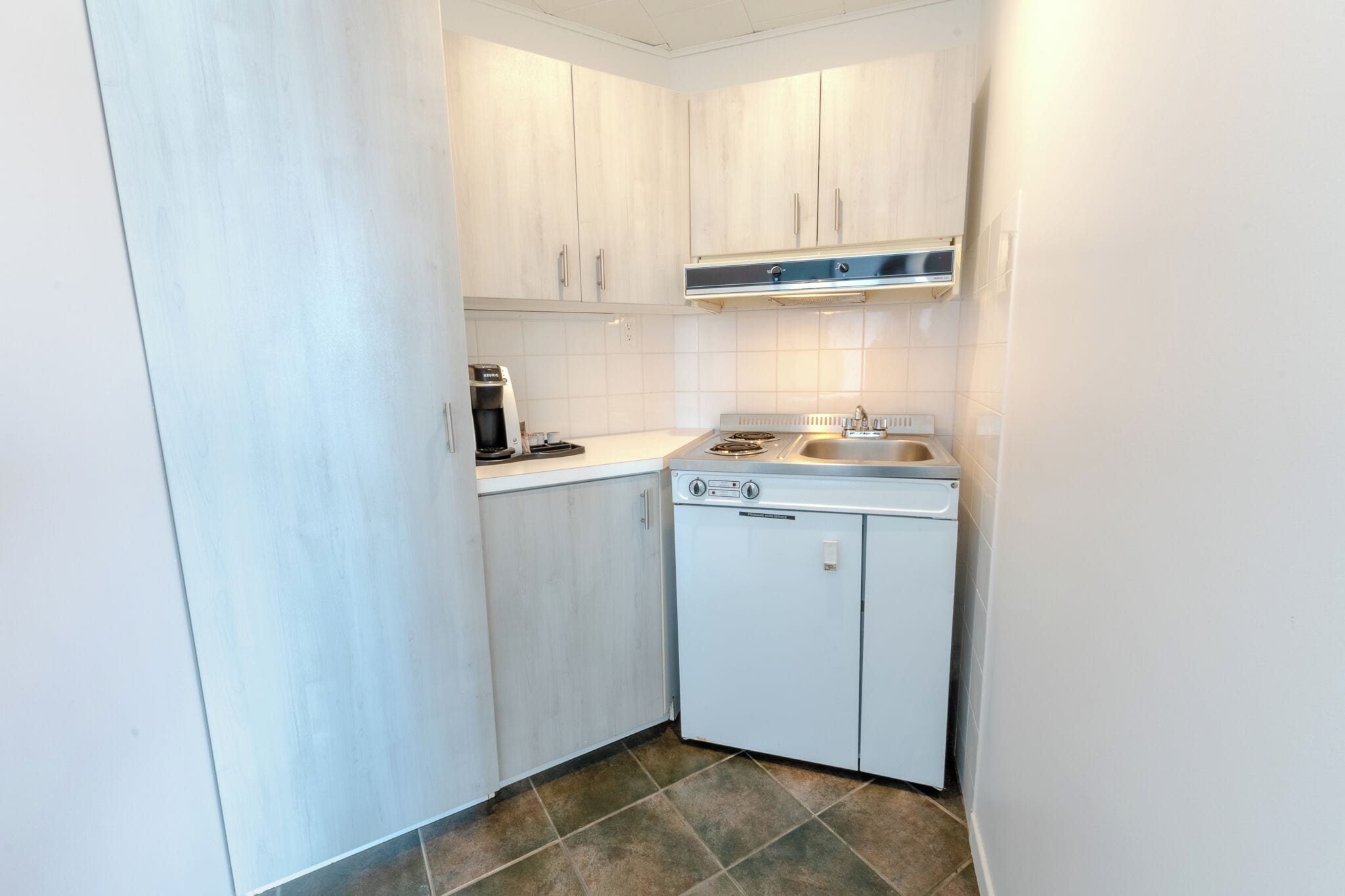 A compact kitchen with white cabinets, a built-in stove, and a dishwasher.