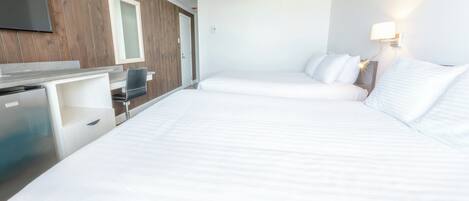 Habitación de hotel con dos camas, un escritorio, un televisor y una lámpara de pared.