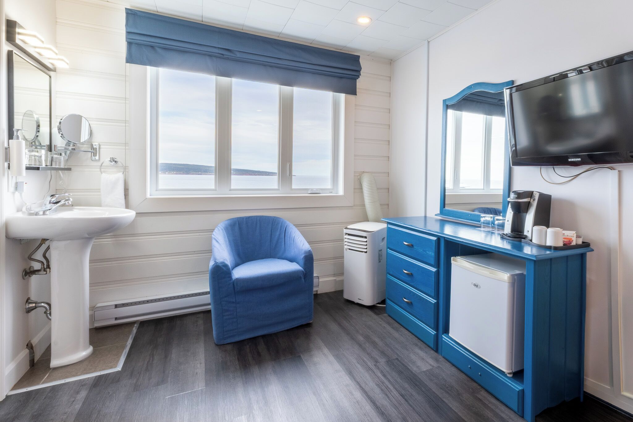A bathroom with a sink, mirror, vanity, and a television.