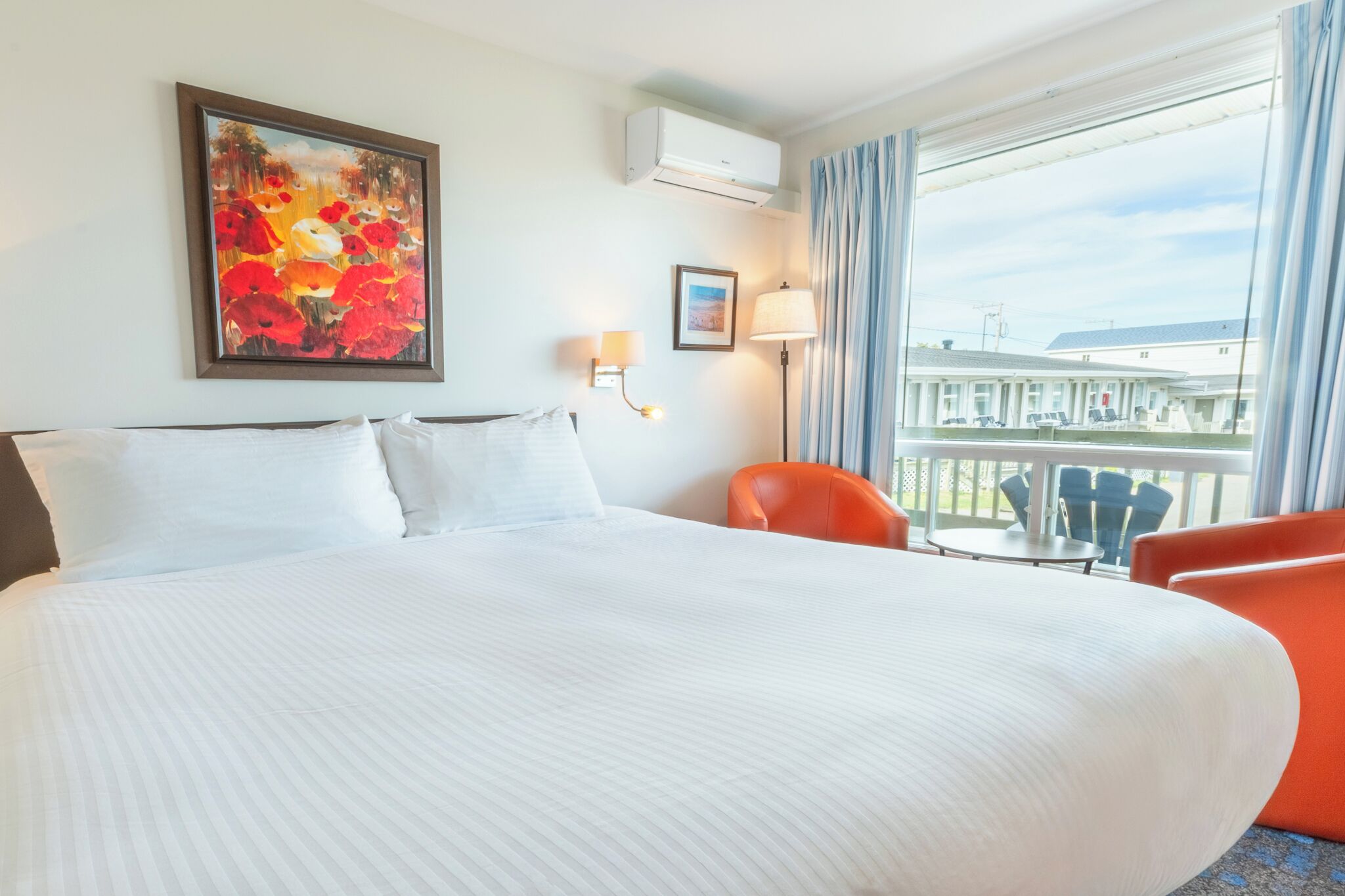 Une chambre d’hôtel avec un grand lit, un tableau au mur, une fenêtre avec des rideaux et une vue sur l’extérieur.