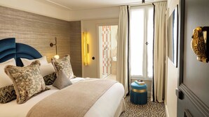 Une chambre d’hôtel avec un grand lit, une tête de lit, une table de chevet et une porte donnant accès à la salle de bain.