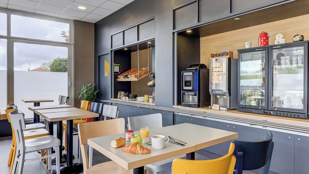 Un café moderno con mesas, sillas, una máquina de café y un refrigerador.