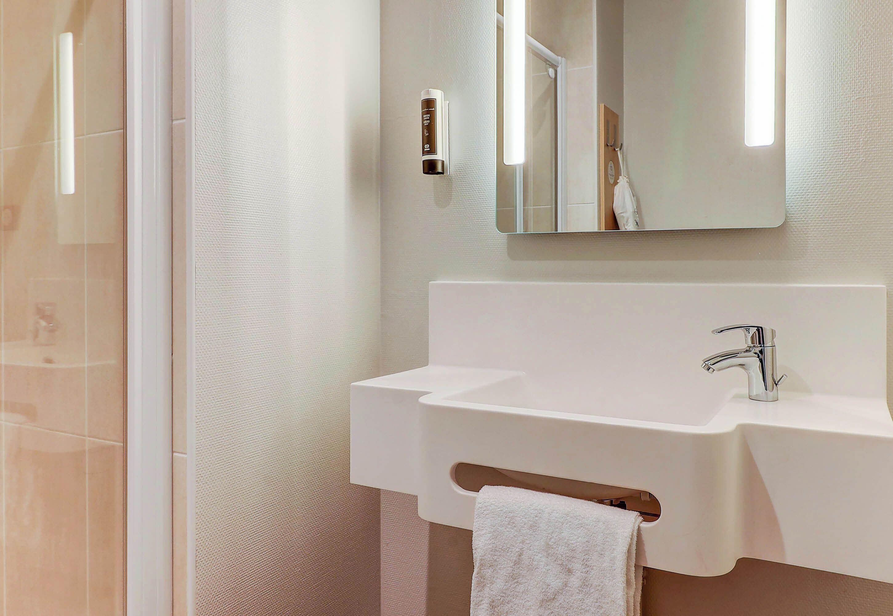 A modern bathroom with a white sink, a mirror, and a towel rack.