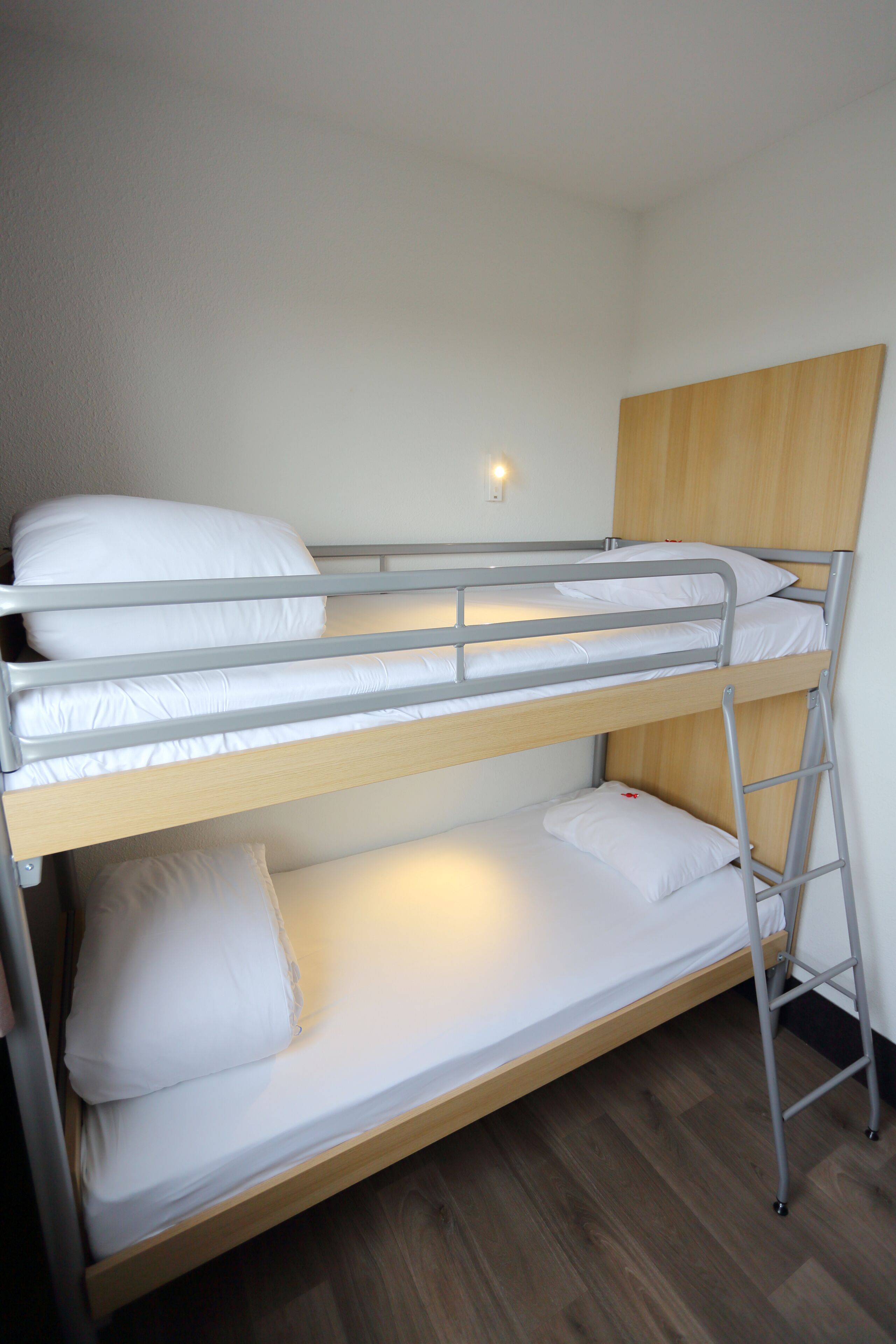 Una cama litera con cabecera de madera y barandillas metálicas.