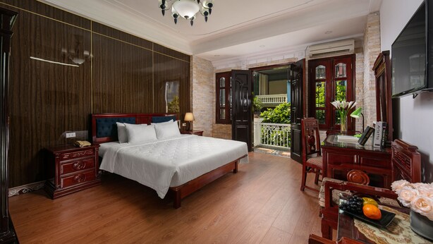 A spacious bedroom with a large bed, wooden furniture, a chandelier, and a balcony with a view. - Little Diamond Hotel (Hanoi)