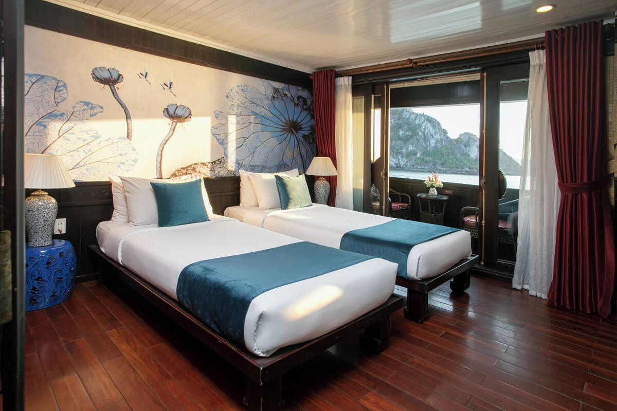 A hotel room with two beds, a large window with curtains, a wall mural, and a wooden floor.