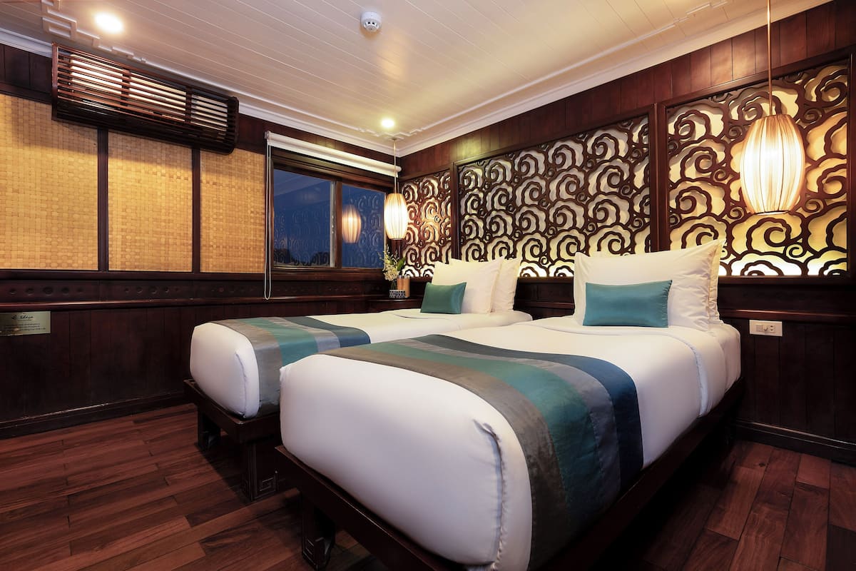 A hotel room with a large bed, wooden paneling, a decorative wall, and a window.