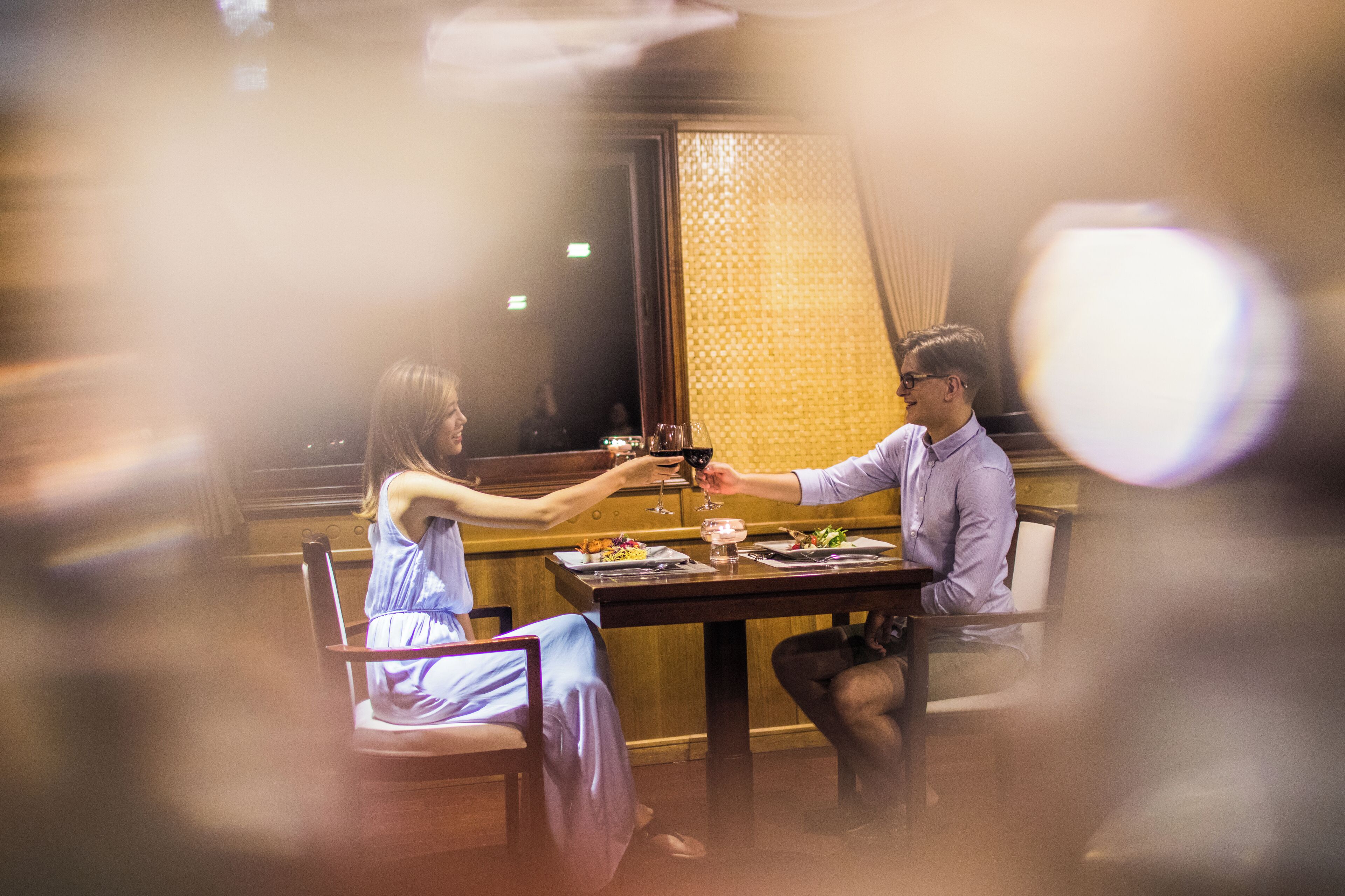 A couple dining at a restaurant with a wooden interior and a patterned wall in the background.