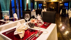 A dining area with tables set for two, featuring red tablecloths and white napkins.