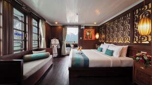 A hotel room with a large bed, a sofa, a view of the mountains, and a painting on the wall.