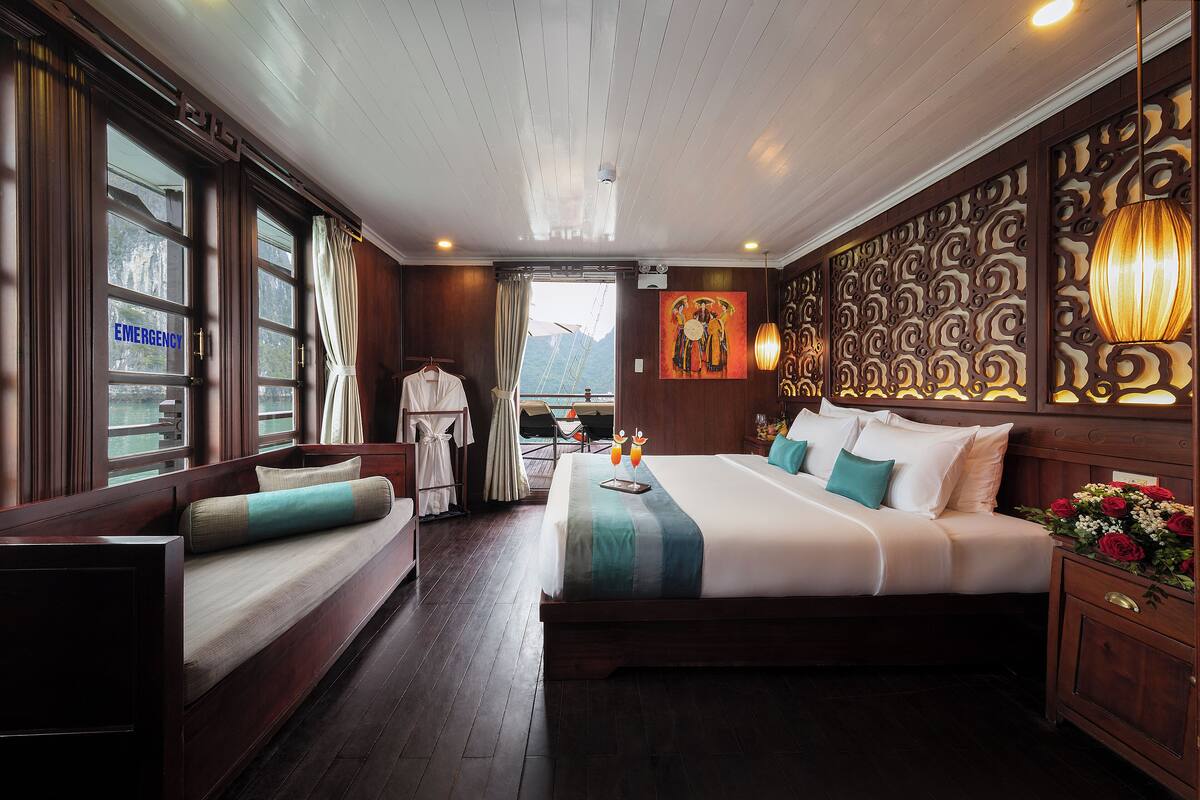 A hotel room with a large bed, a sofa, a view of the mountains, and a painting on the wall.