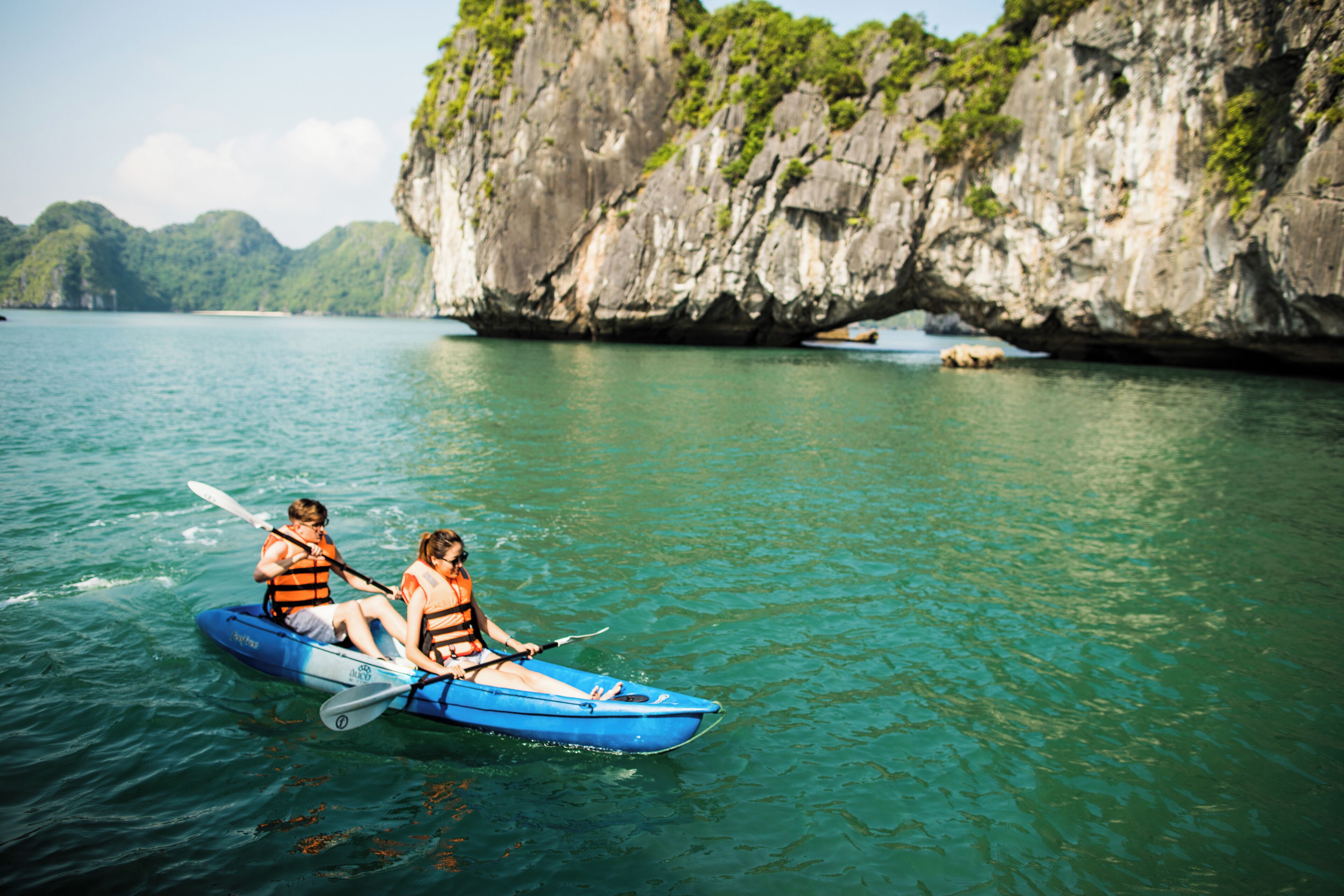 Un kayak sur une étendue d’eau calme, avec une falaise rocheuse en arrière-plan.