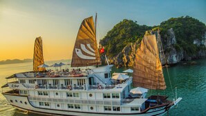 A large, multi-deck boat with a flag, surrounded by calm water and a mountainous landscape.